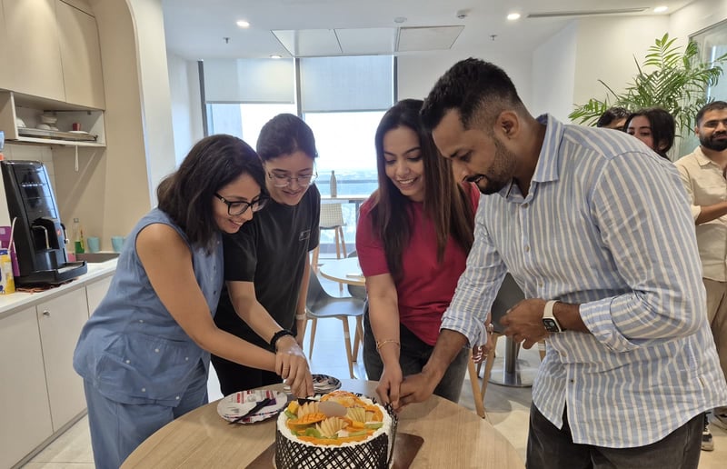 Team members cutting a fruit cake together in the office kitchen